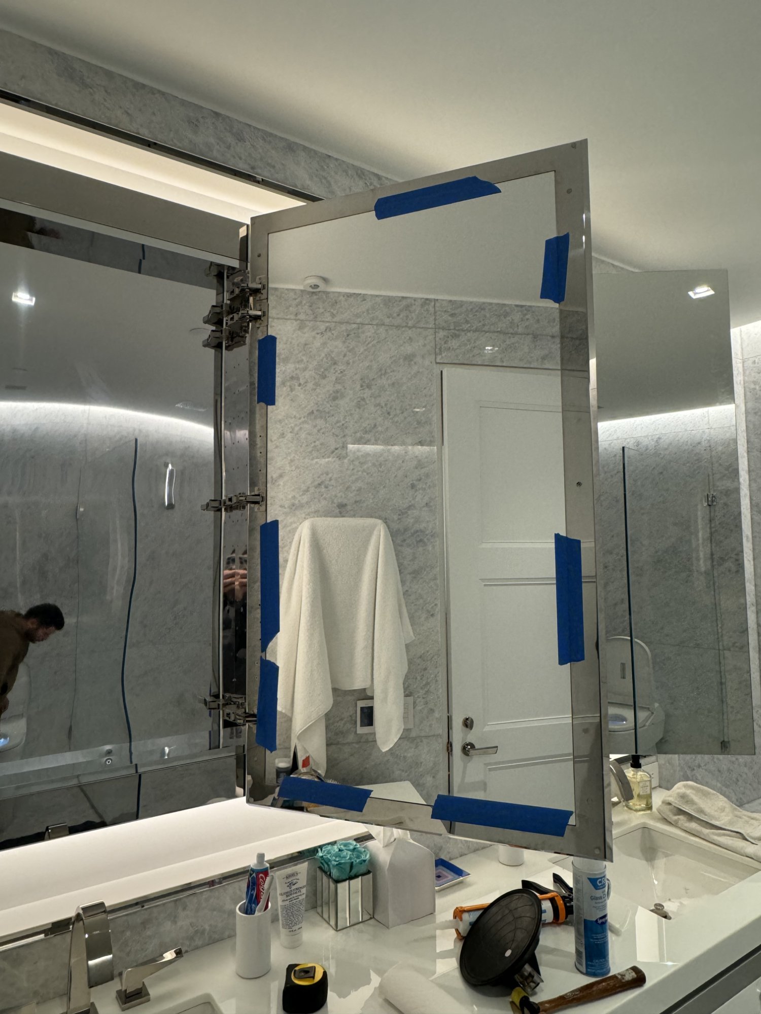 Medicine cabinet mirror replacement in NYC — mirror taped with blue tape during silicone curing period