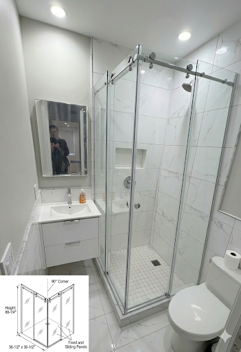 90-degree corner frameless shower enclosure with fixed and sliding panels, chrome hardware, white marble tile NYC bathroom