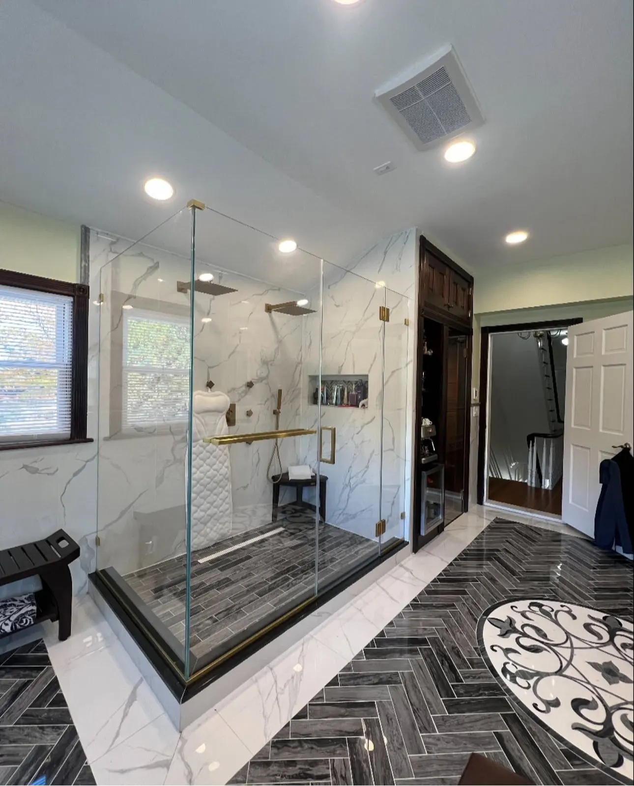 Finished frameless shower enclosure with brass hardware in a tiled bathroom