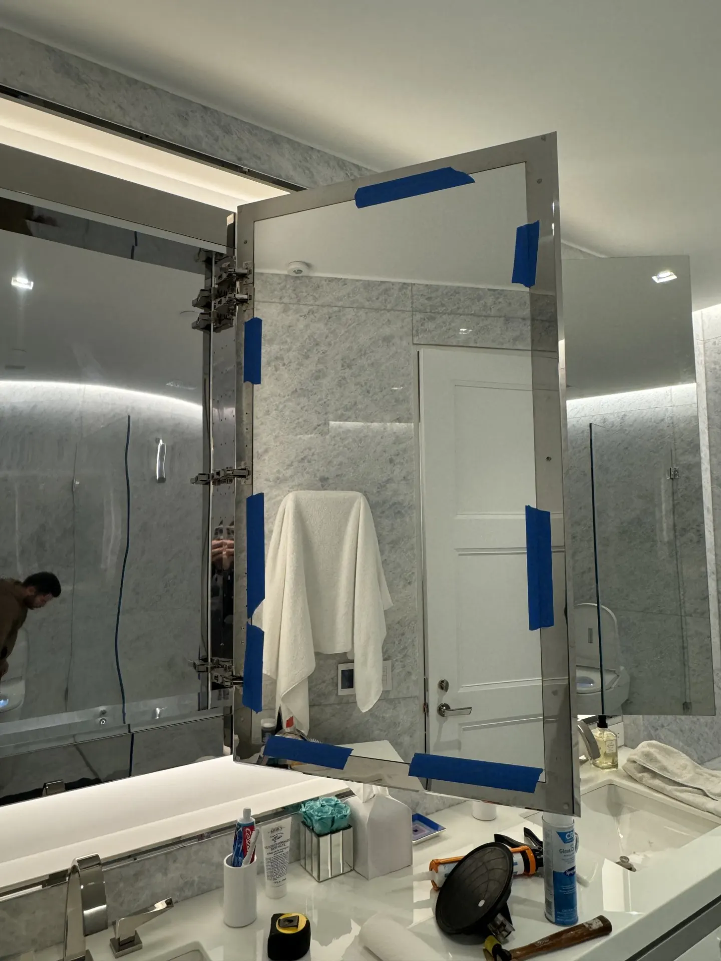 Mirror panel held with blue tape during adhesive curing